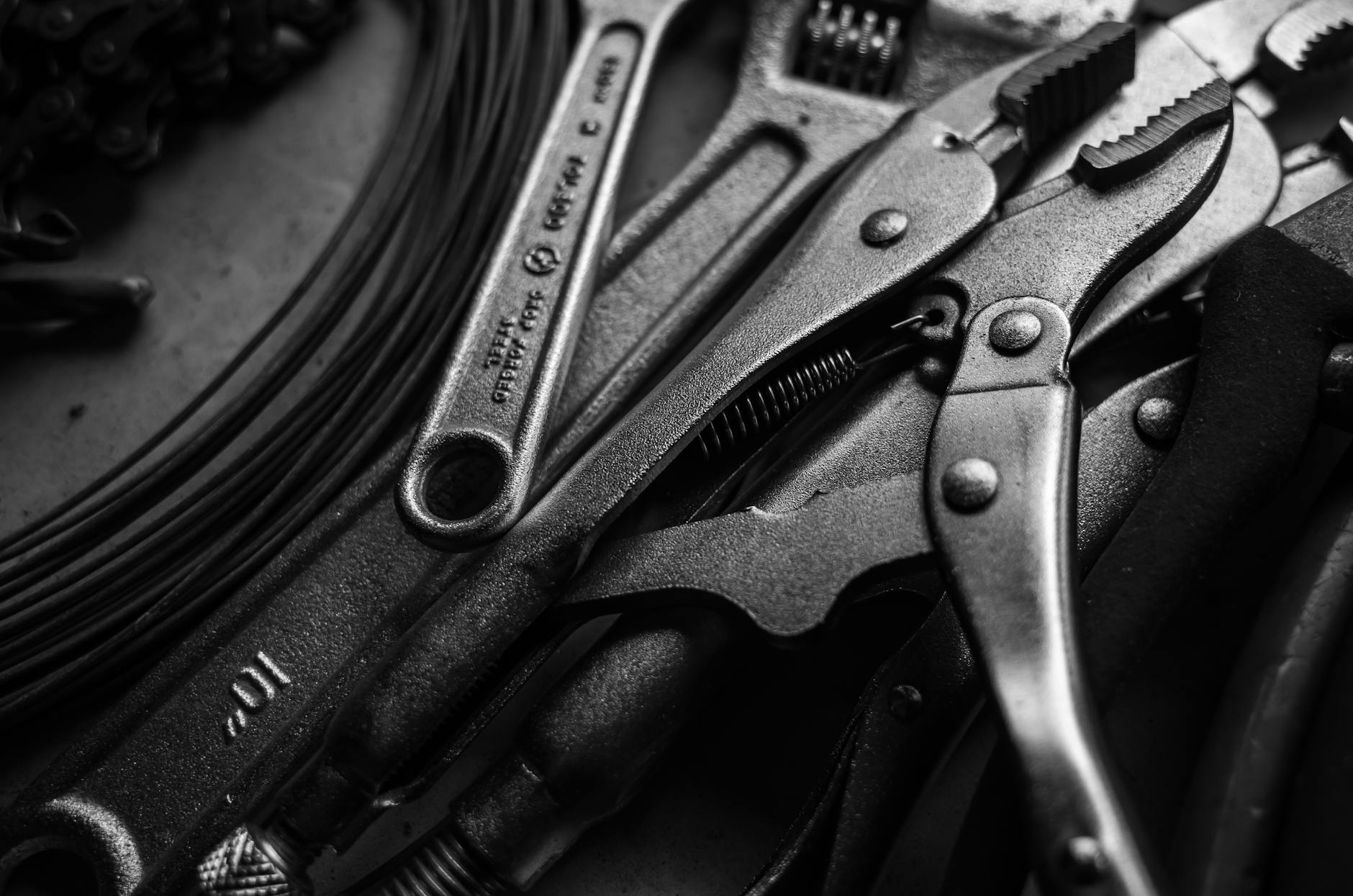 A striking black and white close-up of metal tools, including wrenches and pliers.